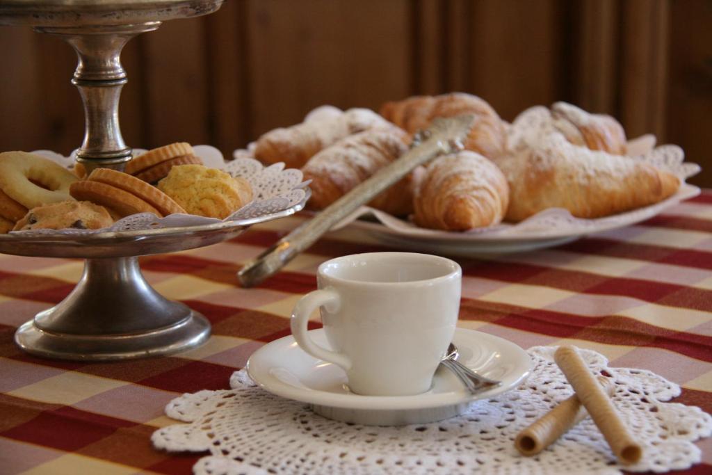 Saldumu plate ar dažādiem konditorejas izstrādājumiem un kafijas krūze uz galda ar pārklāju.