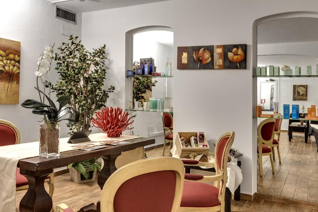 Mūsdienīga un eleganta skaistumkopšanas salona iekārtojums ar dekoratīvām augu kompozīcijām un mākslas darbiem, kas rada relaksējošu atmosfēru. Interjerā redzamas koka mēbeles un gaismas toņi, kas uzsver komfortu un estētiku.