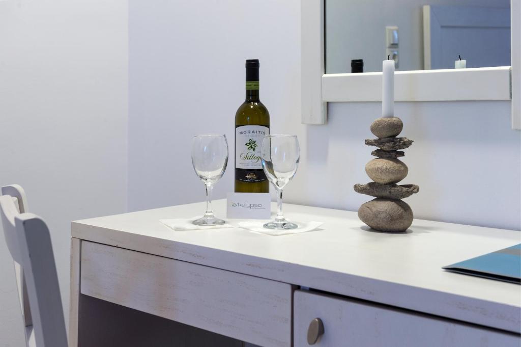 Galda dekorācija ar pudeli baltā vīna, divām glāzēm un akmeņu kompozīciju, kas rada relaksējošu atmosfēru. Ideāla vieta romantiskai vakariņai.