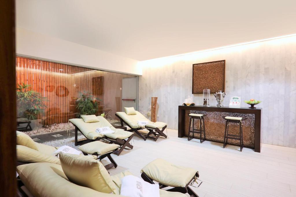 Mūsdienīgs spa atpūtas telpa ar ērtām šūpuļkrēslām, kas izkārtoti ap elegantu bāru. Telpā ir zaļumi un relaksējoša atmosfēra.