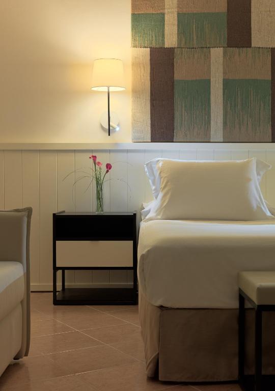 Mūsdienīga guļamistaba ar vienkāršu gultu, naktsgaldiņu un elegantu apgaismojumu, papildināta ar dekoratīvām sīpolēm un māksliniecisku sienas apdari.