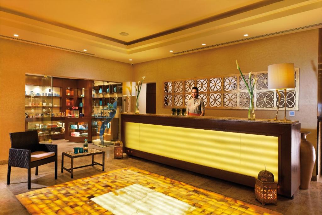 Spa recepcija ar modernu dizainu, gaišām gaismām un elegantiem dekoratīviem elementiem. Interjerā redzami produkti un relaksējoša atmosfēra.