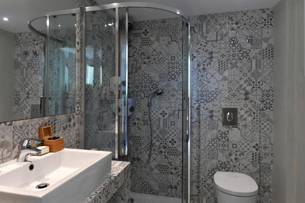 Mūsdienīgs vannas istabas interjers ar elegantu dušas kabīni, pelēku flīžu apdari un minimālistisku izskatu. Vannas istabā ir moderns izlietne un koka uzglabāšanas kaste.