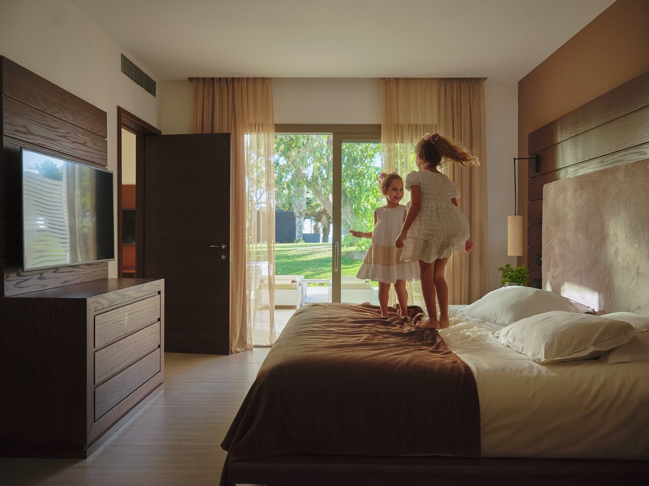 Divi bērni lec uz gultas Mare Ayia Napa viesnīcas numurā.