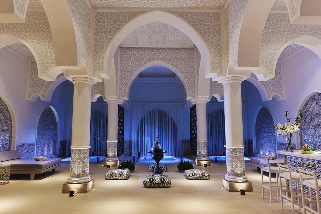 Mūsdienīga spa telpa ar greznām arka formām, dekoratīvām sienām un relaksējošu apgaismojumu, radot mierīgu atmosfēru.