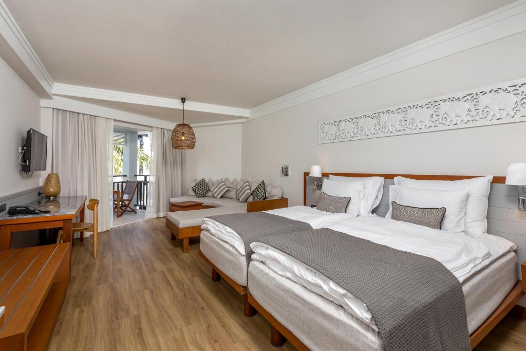 Moderna viesnīcas numura iekārtojums ar divām gultām, ērtu dīvānu un balkonu. Interjeru papildina dabīgi materiāli un gaišas krāsas, radot mājīgu atmosfēru.