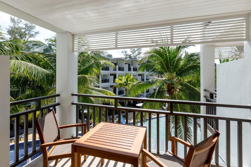 Balkona skats uz palmām un baseinu, ar koka galdu un krēsliem. Ideāla vieta relaksācijai tropiskā vidē.