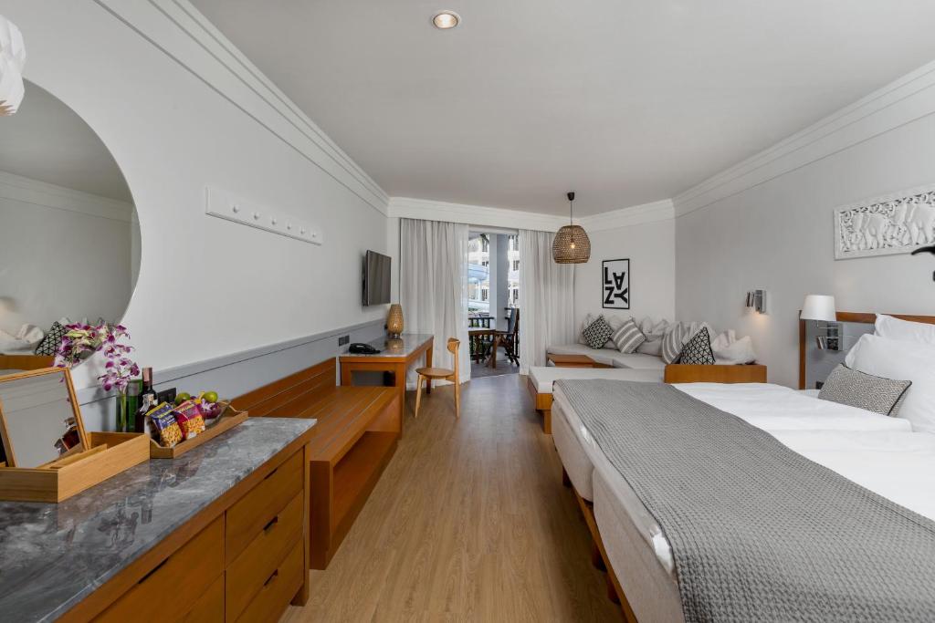 Mūsdienīgs viesnīcas numurs ar plašu gultu, koka mēbelēm un relaksējošu atmosfēru. Telpā ir sēdvietas un logs, kas ved uz āra terasi.