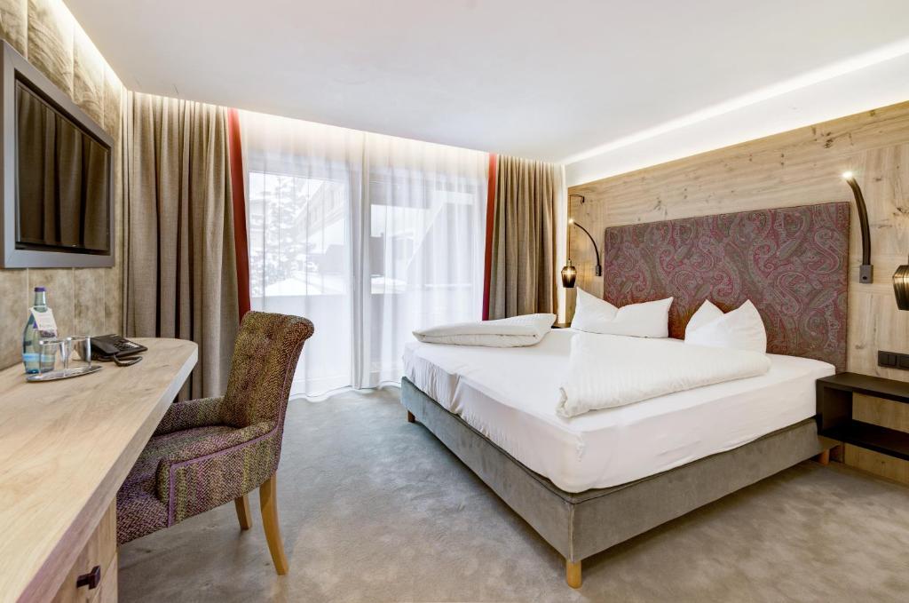 Moderns viesnīcas numurs ar ērtu gultu, koka elementiem un dabīgu apgaismojumu. Numurā ir galda zona un televizors, kā arī lieli logi ar aizkariem.