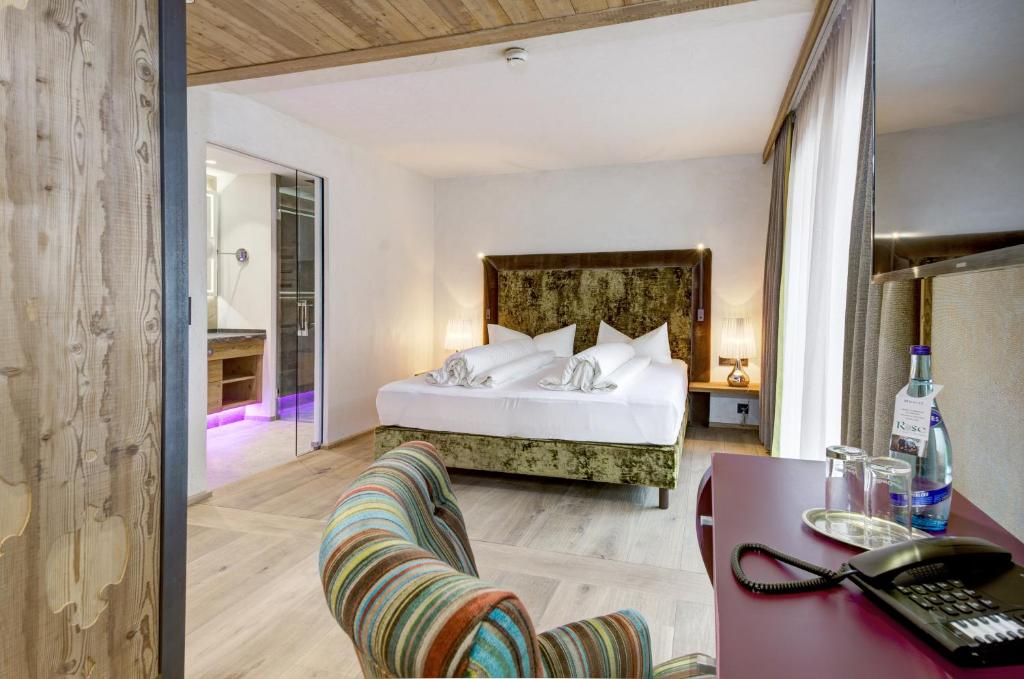 Mūsdienīgs viesnīcas numurs ar elegantu gultu, komfortablu krēslu un mūsdienīgu vannas istabu. Telpa ir gaiša un plaša, radot patīkamu un relaksējošu atmosfēru.