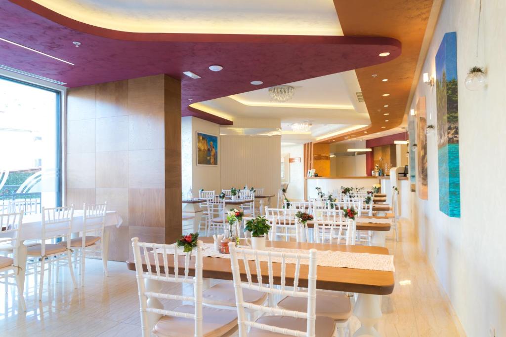 Mūsdienīgs restorāns ar gaišu interjeru, koka galdiem un baltām krēsliem, dekorēts ar ziediem. Telpa ir plaša un gaiša, ar lieliem logiem un mākslas darbiem uz sienām.