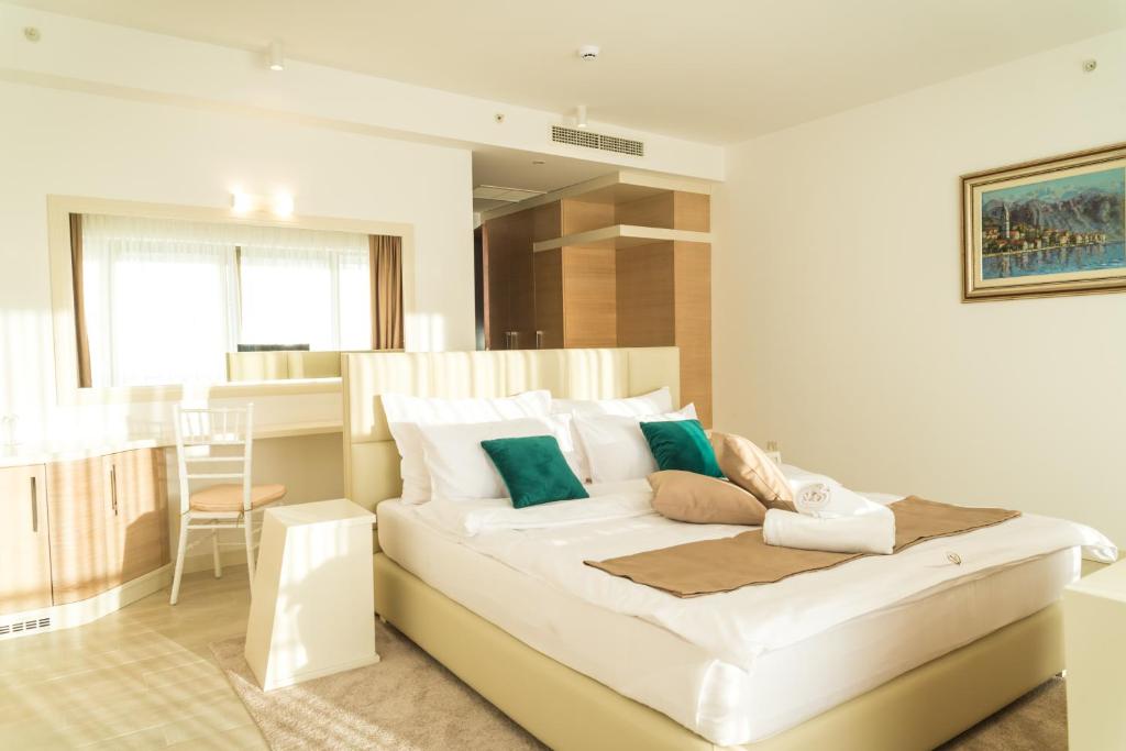 Mūsdienīga guļamistaba ar divguļamo gultu, spilveniem un gaismu piepildīta telpa. Interjerā ir koka mēbeles un liels spogulis, radot harmonisku atmosfēru.