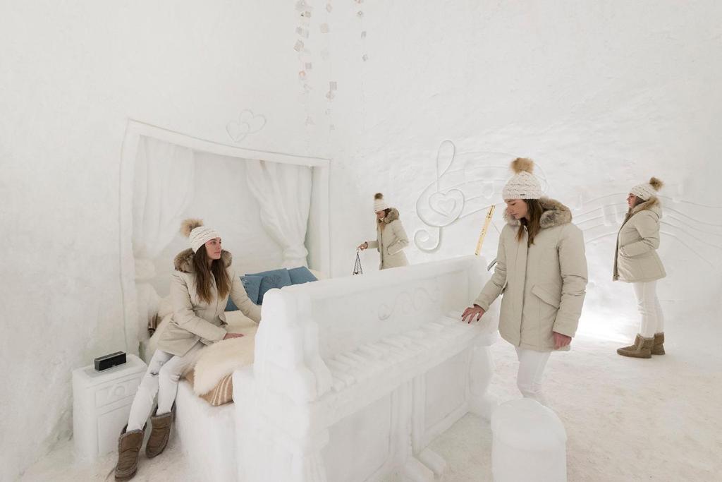 Apsniguša istaba ar ledus mēbeļu elementiem un mūzikas simboliem, kurā jaunā sieviete izbauda ziemas atmosfēru.