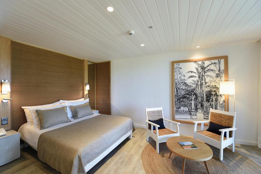 Mūsdienīgs viesnīcas numurs ar ērtu gultu un stilīgām mēbelēm, pievienots mākslas darbs un gaismas avoti, kas rada patīkamu atmosfēru.