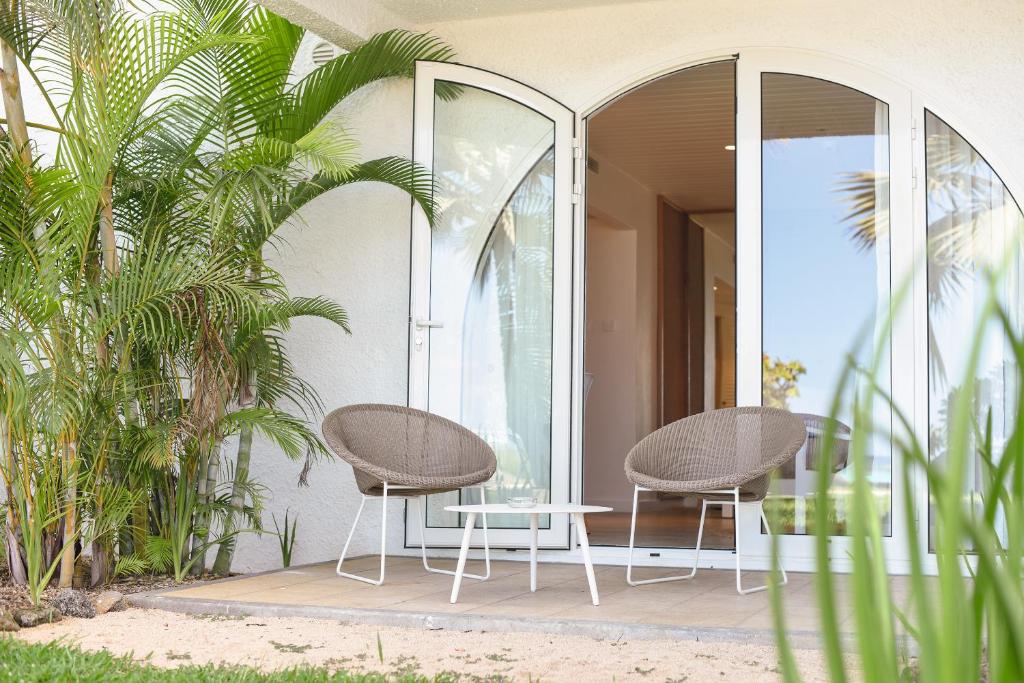 Mūsdienīga terase ar divām ērtiem krēsliem un mazu galdiņu, apkārt augošu zaļumu un saulainu skatu uz dabu.