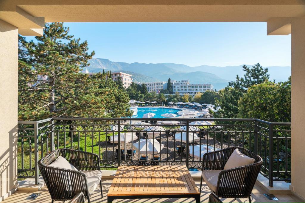 Skats no balkona uz viesnīcas baseinu un apkārtējiem kalniem, ar ērtām krēsliem un galdu. Ideāla vieta relaksācijai un atpūtai.