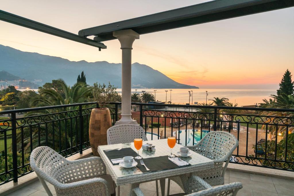 Terases skats uz jūru un kalniem ar brokastu galdu, uz kura ir oranžs dzēriens un kafijas tasītes. Saullēkta gaisma rada mierīgu atmosfēru.