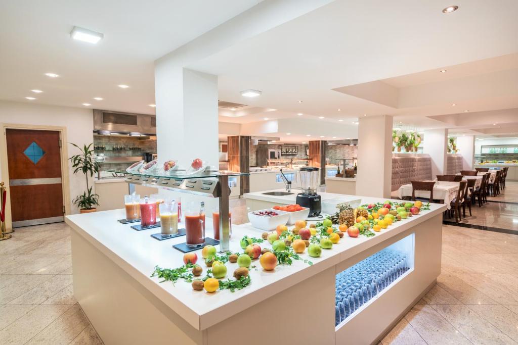 Svaigu augļu un dzērienu bārs modernā restorānā, ar dažādām sulām un augļiem uz letes. Interjers ir gaišs un viesmīlīgs, radot patīkamu atmosfēru.