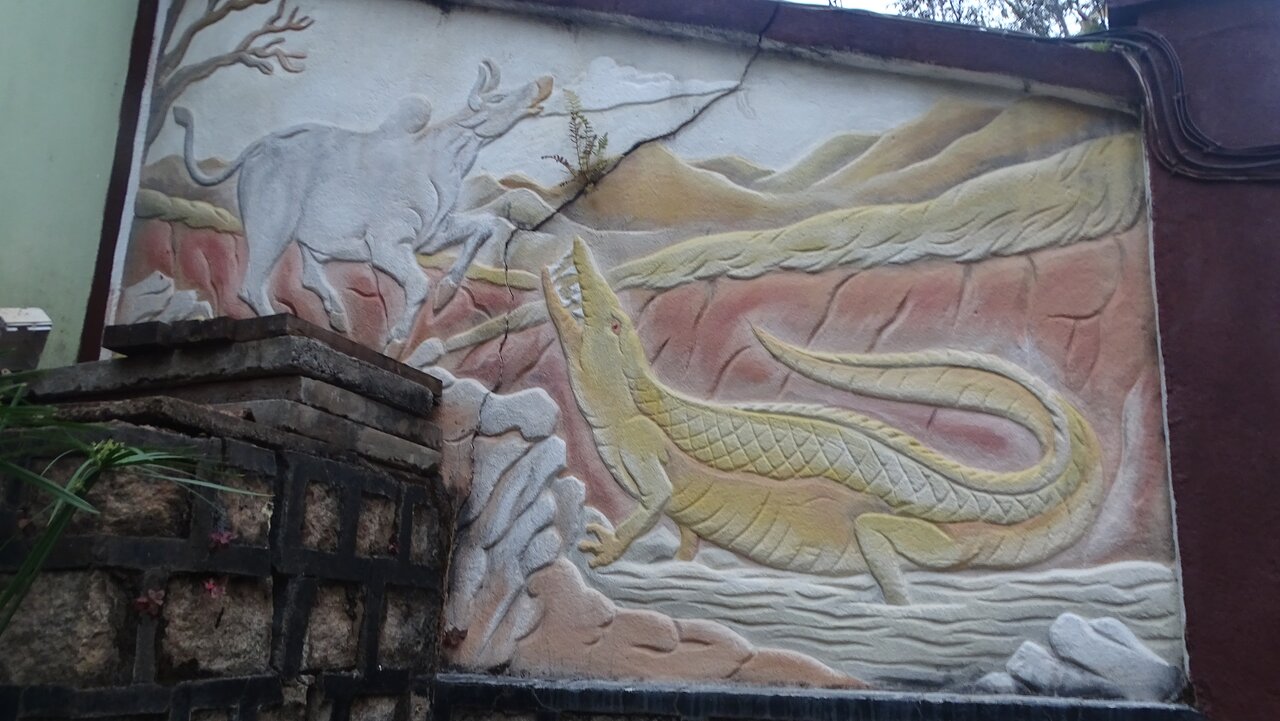 Reljefa sienas mākslas darbs ar krokodilu un ziloņu.