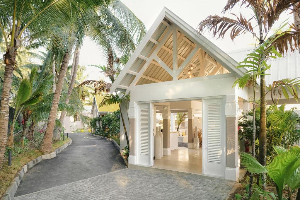 Mūsdienīga viesnīcas ieeja, apzaļumota ar palmām un ziediem, kas rada tropisku atmosfēru. Gaismas elementi un plašas telpas veicina siltu un aicinošu noskaņu.