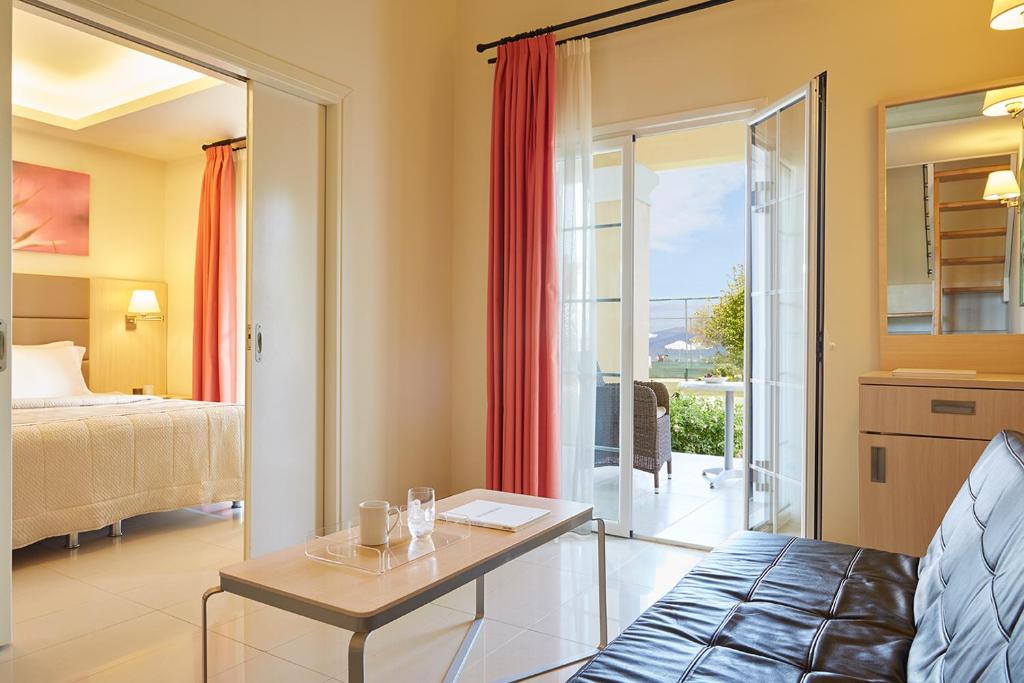 Mūsdienīgs viesnīcas numuriņš ar ērtu dīvānu, galdu un skatu uz dārzu. Iekārtots ar siltām krāsām un logiem, kas ved uz terasi.