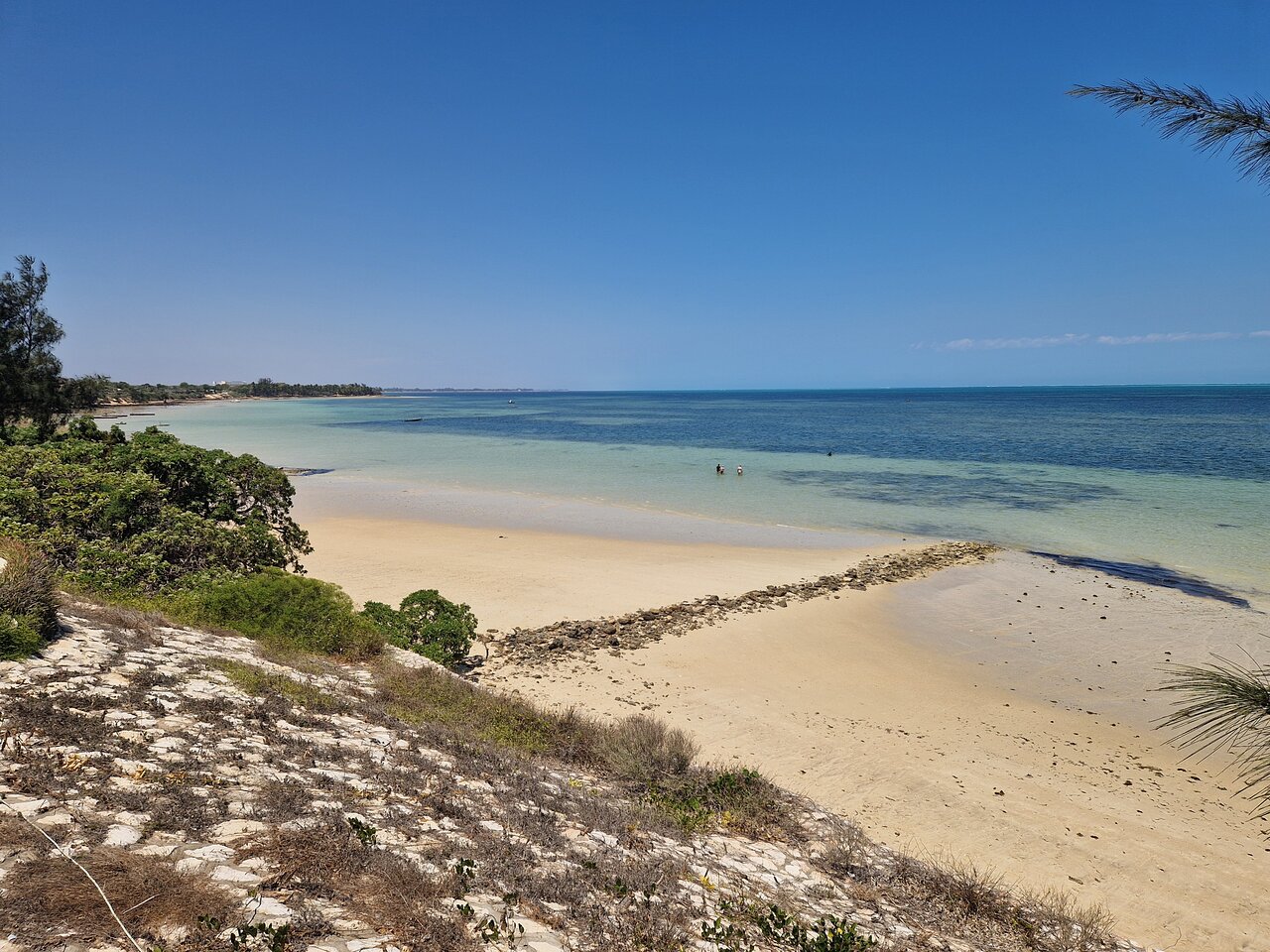 Pludmale pie La Mira de Madiorano ar skaidru zilu debesu fonu.