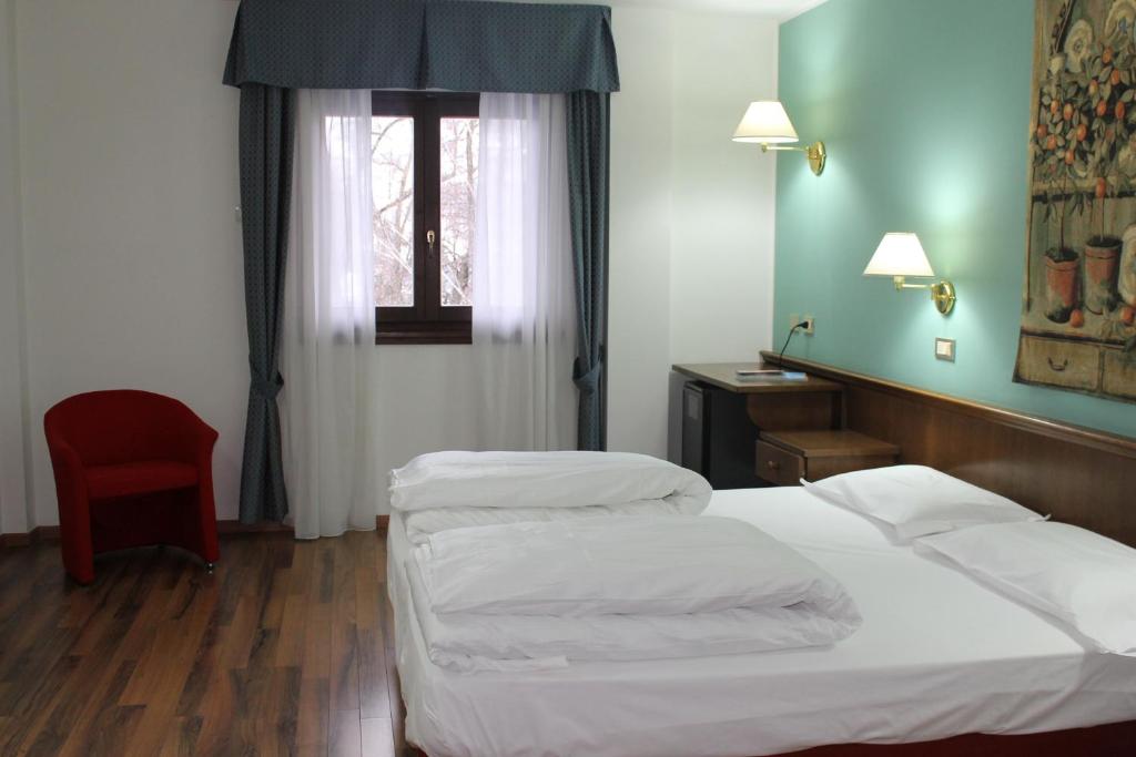 Mūsdienīga viesnīcas numura iekārtojums ar divguļamo gultu, sarkanu krēslu un logu ar vieglām aizkariem. Sienas ir krāsotas gaiši zaļā tonī, radot patīkamu atmosfēru.