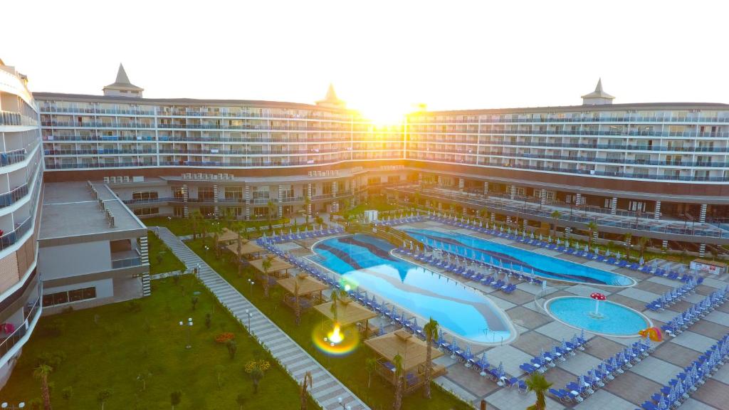 Mūsdienīgs viesnīcu komplekss ar vairākiem baseiniem un sauļošanās zonām, apgaismots saulrieta gaismā. Ideāla vieta atpūtai un relaksācijai.