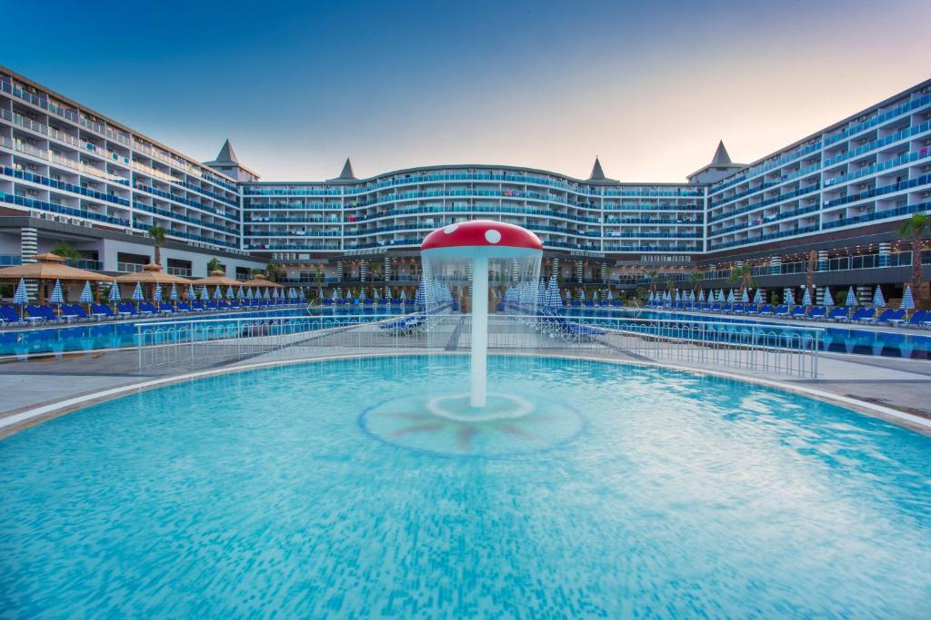 Elegants viesnīcas komplekss ar baseinu un strūklaku, apkārt ar sauļošanās krēsliem un šūpuļkrēsliem. Ideāla vieta relaksācijai un atpūtai.