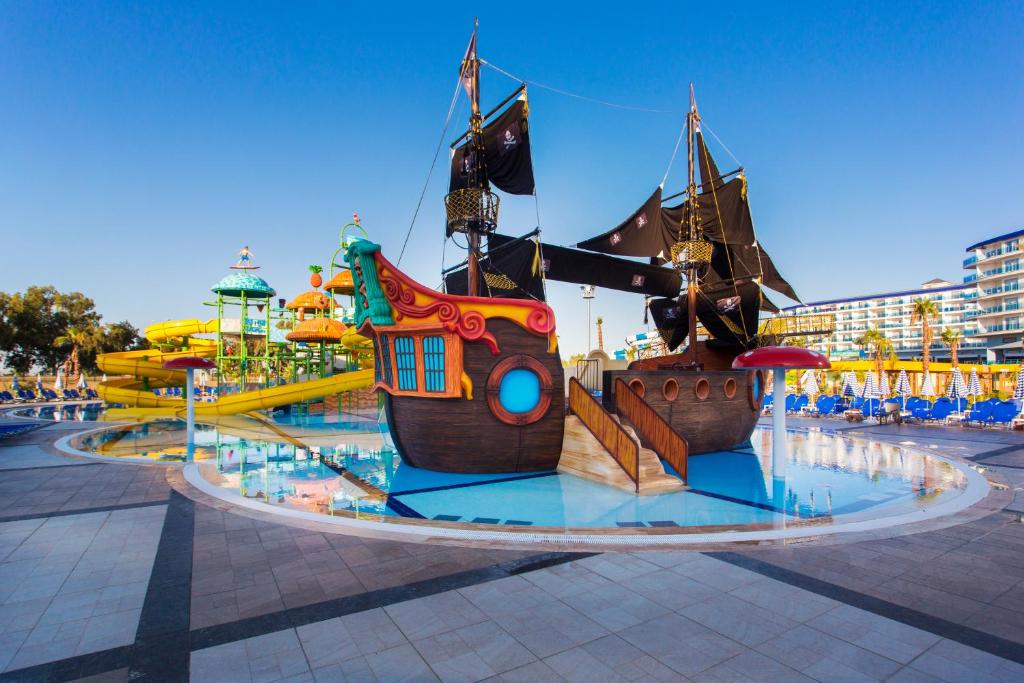 Ūdens atrakciju parks ar kuģa dizaina spēļu zonu un krāsainām slidkalniņām, kas piemērots bērniem un ģimenēm. Peldbaseins ir skaidrs un saulains, radot jautru atmosfēru.