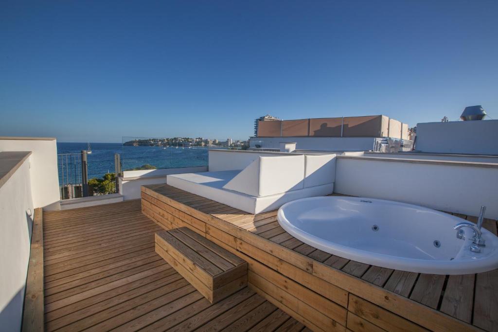 Terases zona ar koka grīdu un siltu ūdens burbuļvannu, skats uz jūru un pilsētas ainavu.