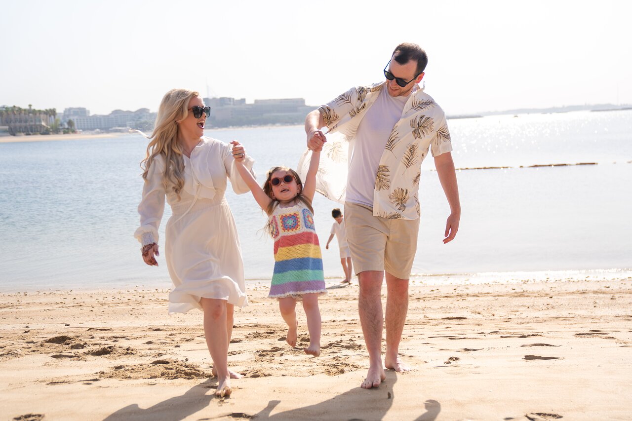 Andaz Dubai The Palm pludmale ar laimīgu ģimeni pie jūras.