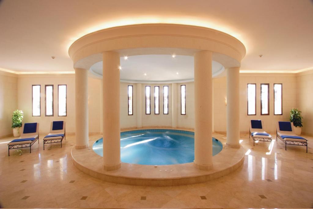 Mūsdienīgs spa telpa ar apaļu baseinu un komfortablām atpūtas krēslām, apgaismotu ar siltu gaismu. Ideāla vieta relaksācijai un atpūtai.