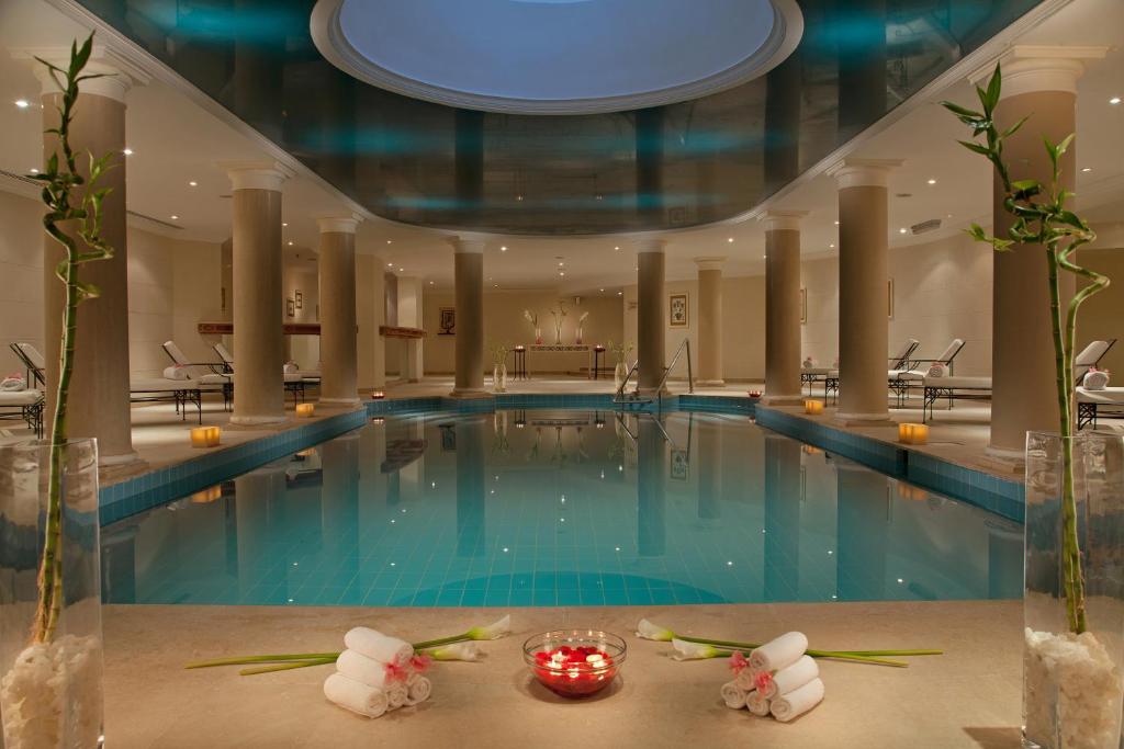 Luksusa spa telpa ar mierīgu peldbaseinu, apgaismojumu un ziedu dekorācijām. Ideāla vieta relaksācijai un atjaunošanai.