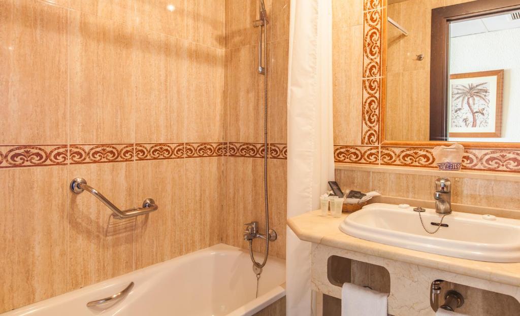 Vannas istaba ar dušu un vannu, dekorēta ar smilšainu flīžu apdari un sarkanu ornamentu. Uz izlietnes atrodas higiēnas piederumi un spogulis.