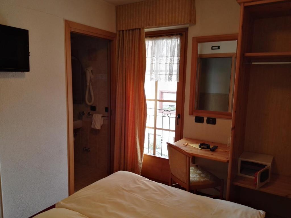 Maza viesnīcas istaba ar gultu, televizoru, rakstāmgaldu un skatu uz logu. Istabā ir arī vannas istaba un dažādi mēbeļu elementi.