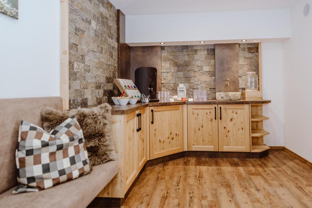 Mūsdienīga virtuve ar koka mēbelēm, akmens apdari un ērtu sēdvietu. Uz galda ir dažādi trauki un dzērienu izsniegšanas stacija.