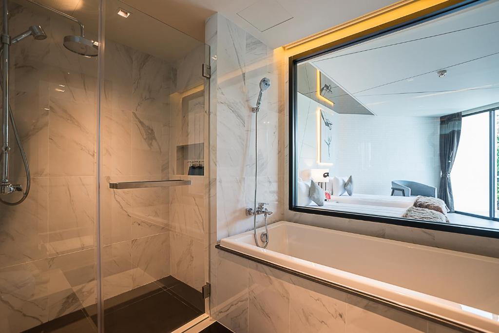 Mūsdienīgs vannas istabas interjers ar stikla dušu un vannu, kas nodrošina lielisku skatu uz guļamistabu. Eleganti akcenti un marmora apdare rada relaksējošu atmosfēru.