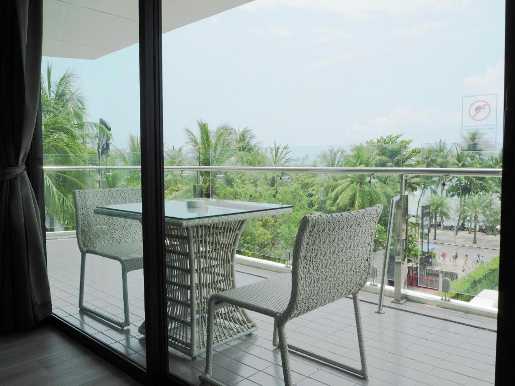 Mūsdienīgs balkons ar skatu uz jūru, kurā ir galds un divas krēsli, apzaļumots ar palmām un zāli. Ideāla vieta relaksācijai un atpūtai.