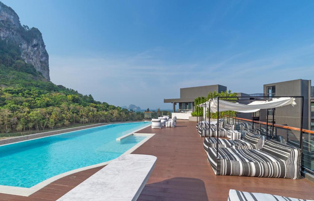 Panan Krabi Resort baseins ar kalnu fonā un atpūtas zonu piekrastē.