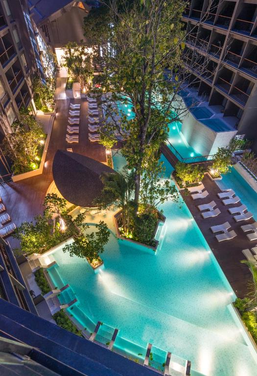 Panan Krabi Resort baseins ar tropu augiem un atpūtas krēsliem.