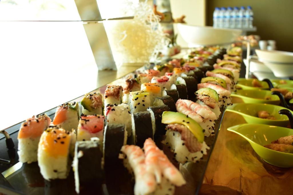 Svaigu sushi šķirņu rinda uz elegantas pasniegšanas plāksnes, ar kraukšķīgu jūraszāļu un garneles dekorāciju. Ideāli piemērots gastronomijas mīļotājiem.