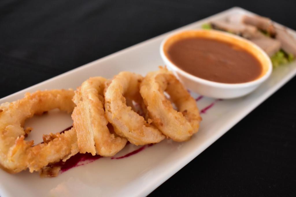 Cepta kalmāra ar mērci un garnelēm, pasniegta uz balta šķīvja.