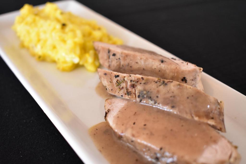 Gara cepta šķiņķa šķēles ar krēmīgu mērci un dzeltenu rīsu piedevu.