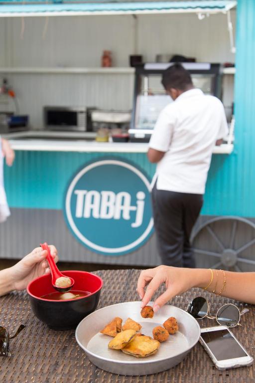 Svaigi pagatavoti uzkodu šķīvji un cilvēks, kas strādā ēdināšanas furgonā ar zīmolu "TABA-j".