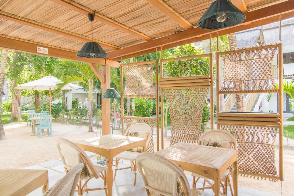 Kafejnīcas terase ar dabīgu apgaismojumu, rotāta ar koka mēbelēm un dekoratīvām sietu konstrukcijām, kas rada patīkamu un relaksējošu atmosfēru.