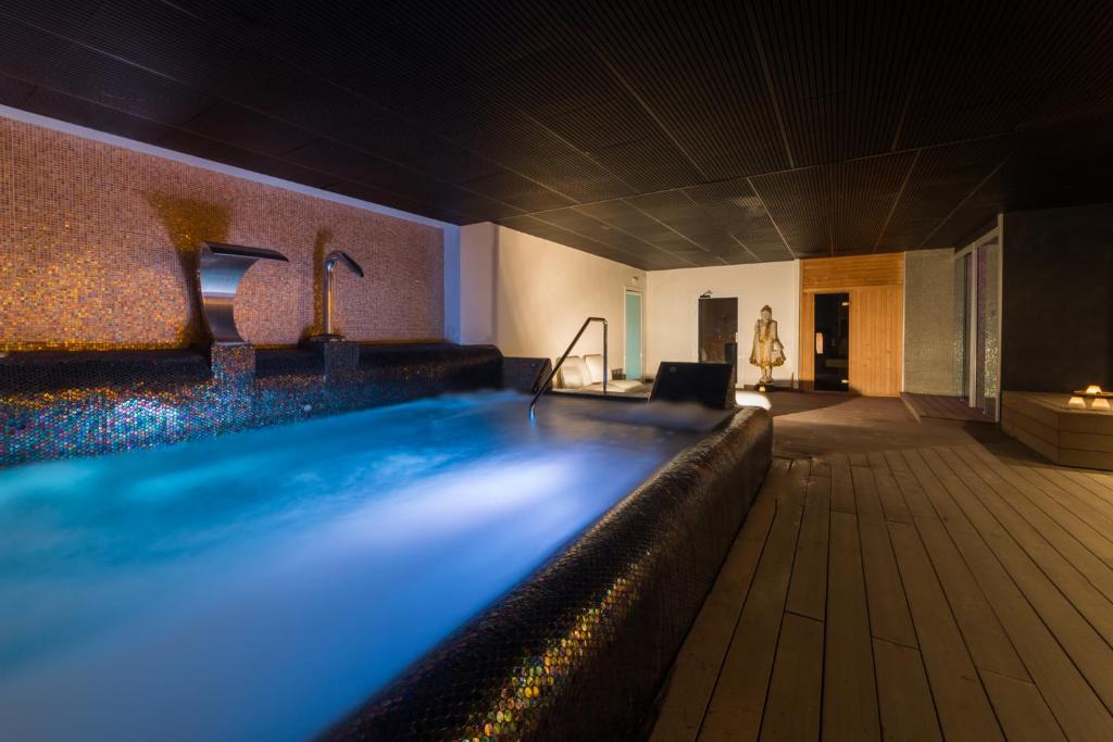 Mūsdienīgs spa ar relaksējošu baseinu, kas apgaismots ar maigu zilo gaismu, un elegantiem ūdens strūklakām. Telpa ir izsmalcināti iekārtota, radot mierīgu atmosfēru.