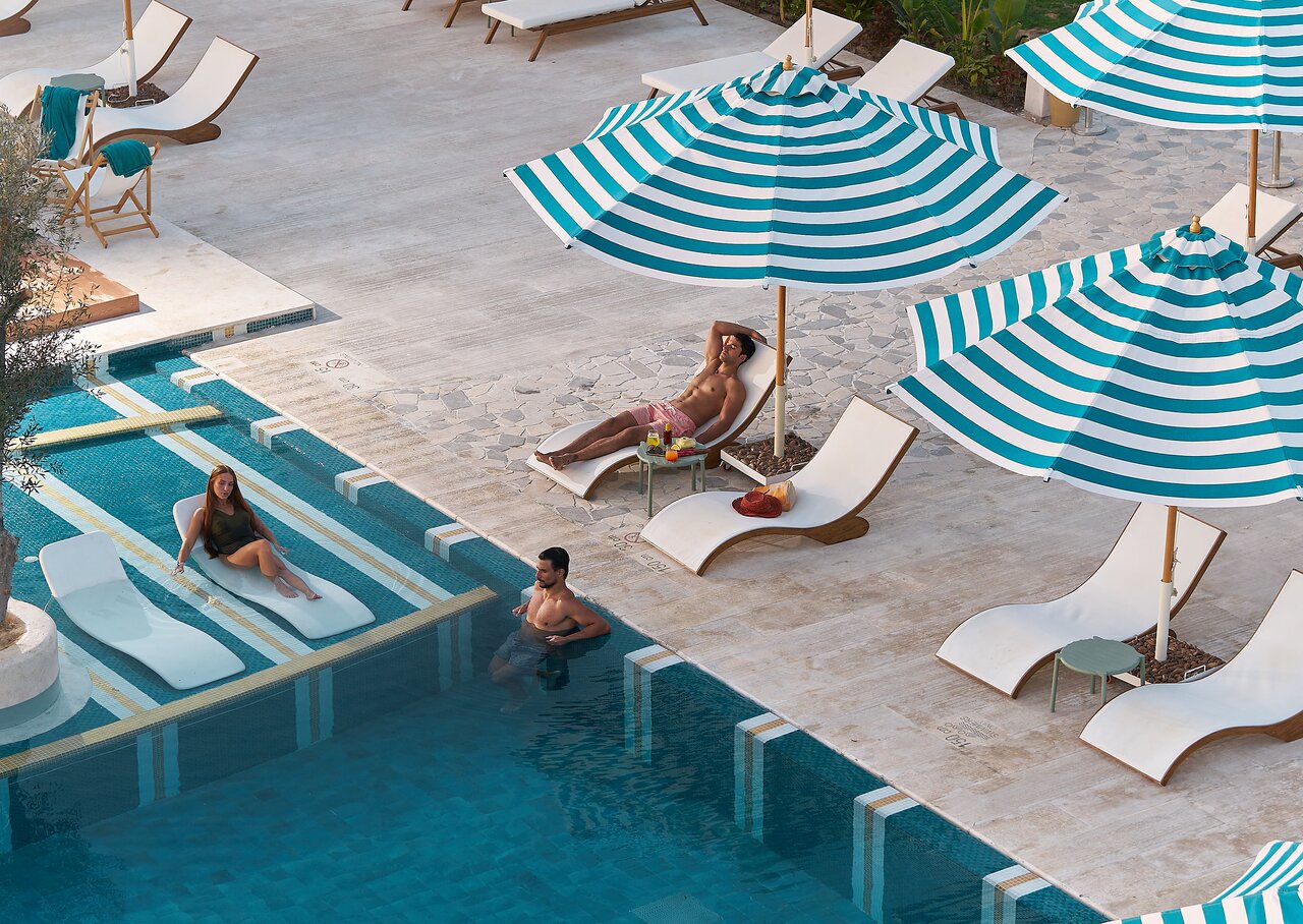 Desert Rose Resort baseins ar atpūtas krēsliem un saulessargiem