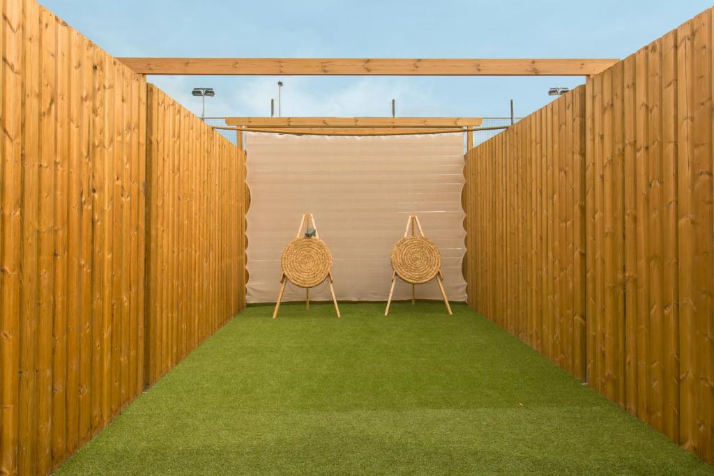 Koka žogu apņemts laukums ar mākslīgo zāli un divām mērķa plāksnēm, kas atrodas centrā. Gaisa telpa ir gaiša un atvērta, radot mierīgu atmosfēru.