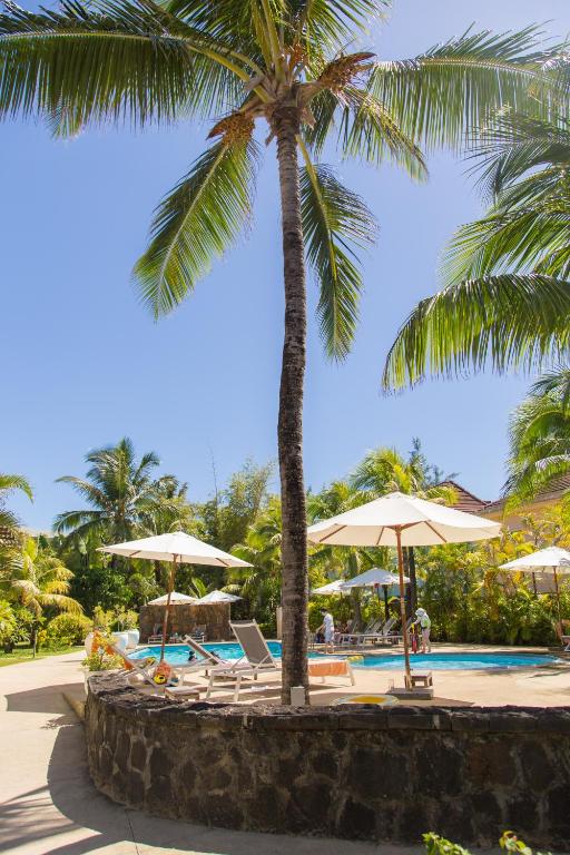 Tropu ainava ar peldbaseinu, palmām un saulessargiem, radot relaksējošu atmosfēru. Ideāla vieta atpūtai un atvaļinājumam.